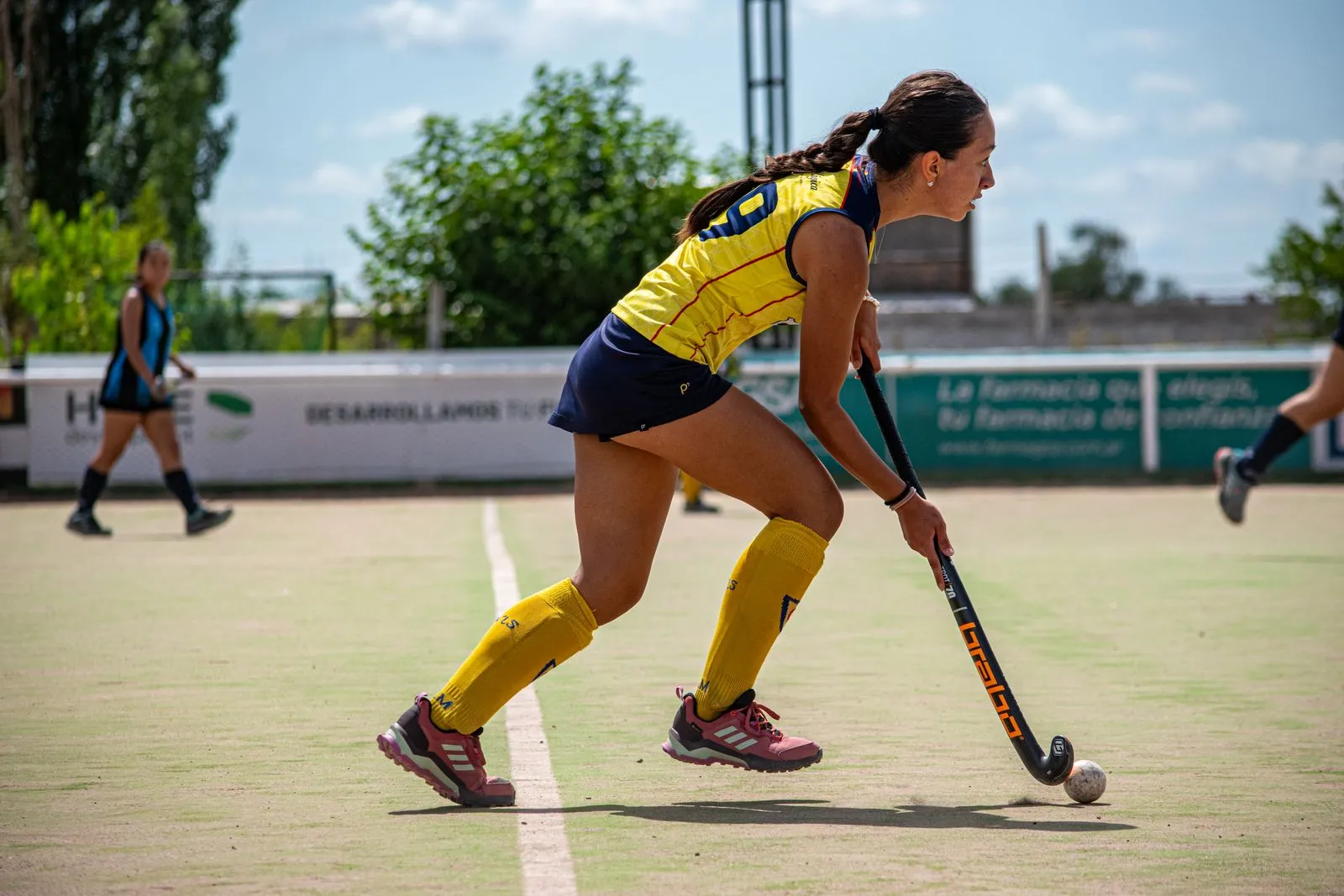 Young female athlete playing field hockey on a sunny day.